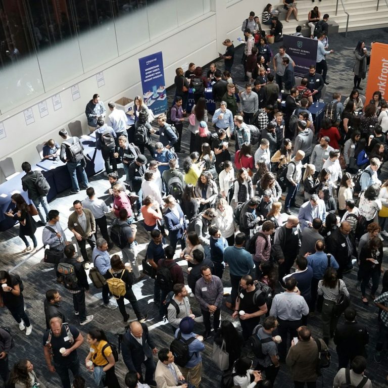 Gran multitud de personas reunidas en un evento con mesas y exhibiciones.